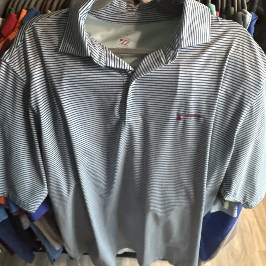 Striped golf polo hanging on a crowded thrift store rack